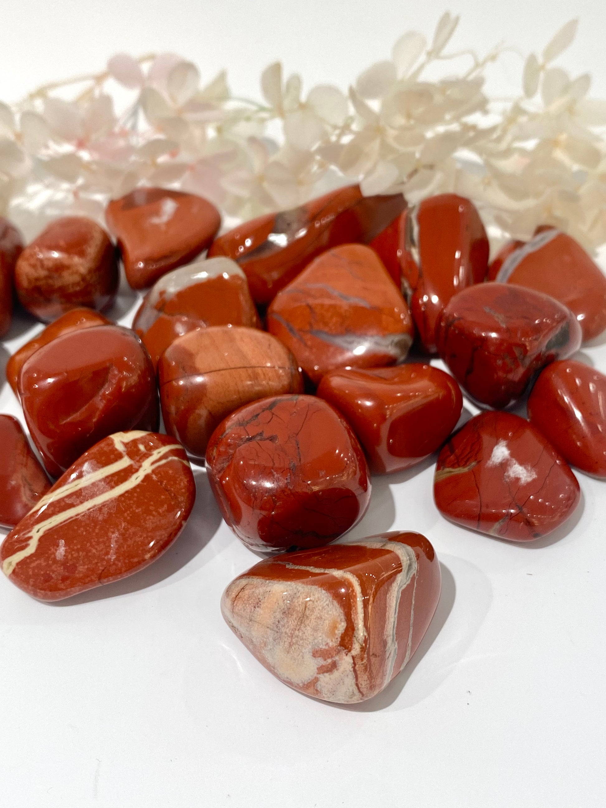 Jasper tumblestones in rich, rust red with black, grey and sand-coloured veins.