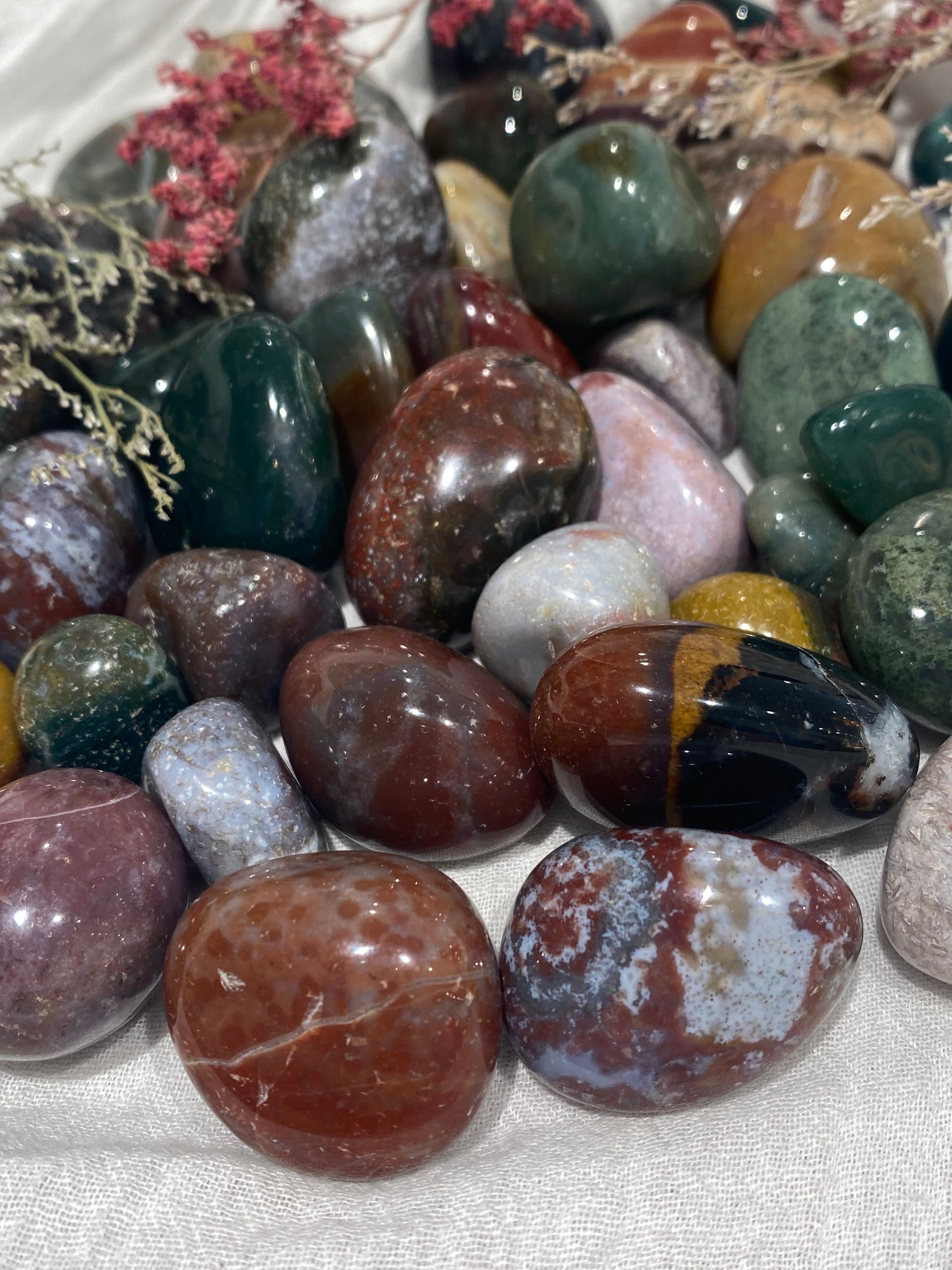 Ocean jasper crystal tumbled stones in earthy shades of rust red, mustard yellow, pine greens, greys and dusty pinks.