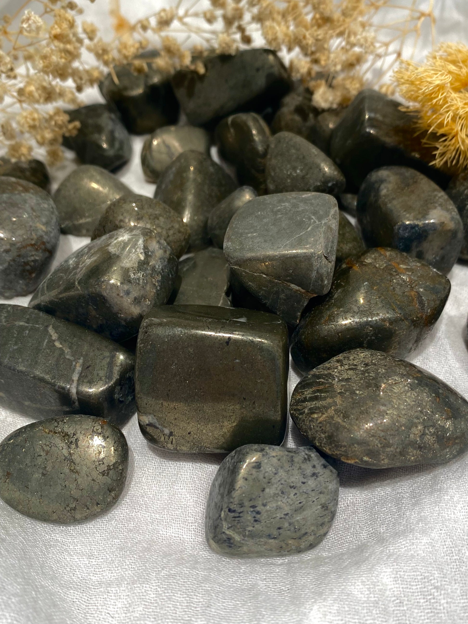 Pyrite tumbled stones in dark browns and greys with a gold sparkle where they catch the light.