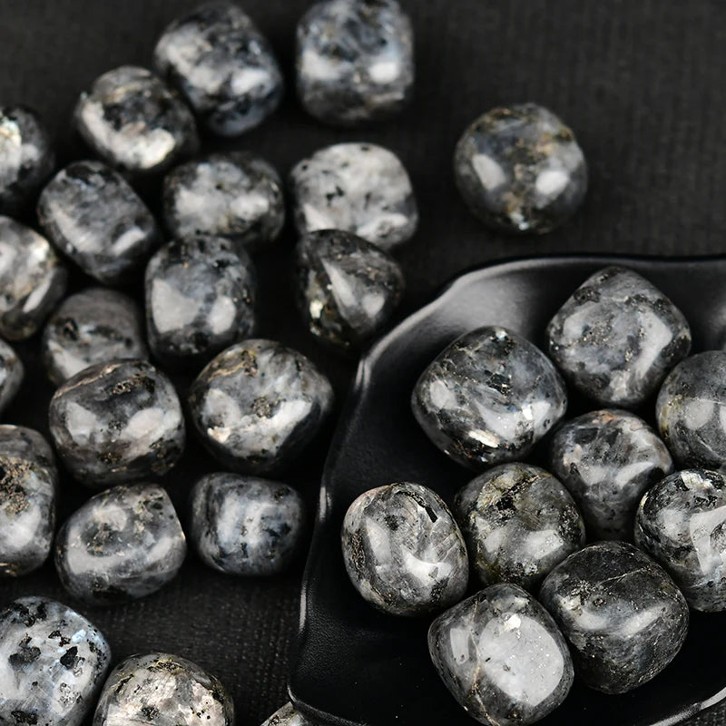 Larvikite tumbled stones in marbled black and grey, reflecting the light.