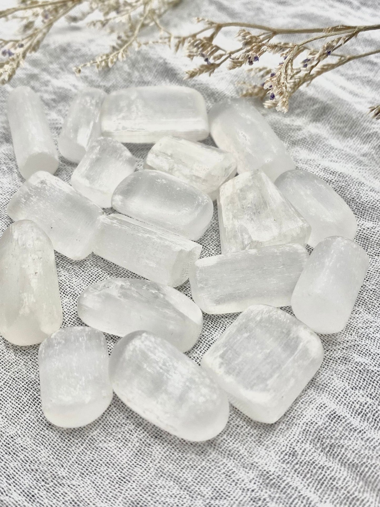 Several small crystal selenite tumbled stones in a pile.