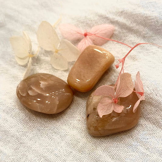Three small tumbled peach moonstones, each in different shapes.