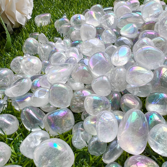 Scattered angel aura quartz tumbled stone crystals shining purple and blue in the light.