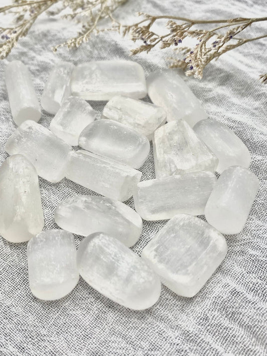 Several small crystal selenite tumbled stones in a pile. 