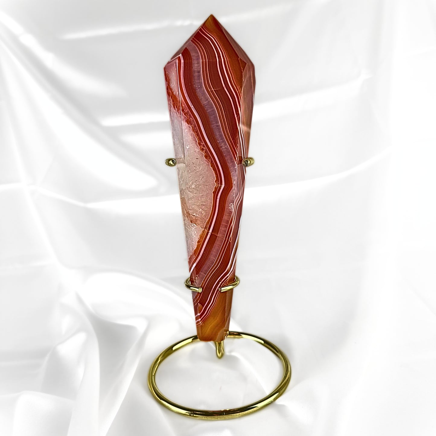 Decorative Red Agate Crystal Wand with red, brown, and white patterns. The crystal wand is displayed in a golden crystal wand display stand. 