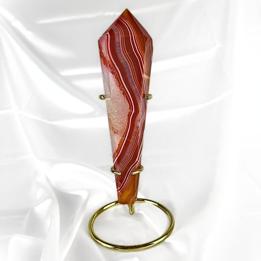 Decorative Red Agate Crystal Wand with red, brown, and white patterns. The crystal wand is displayed in a golden crystal wand display stand. 